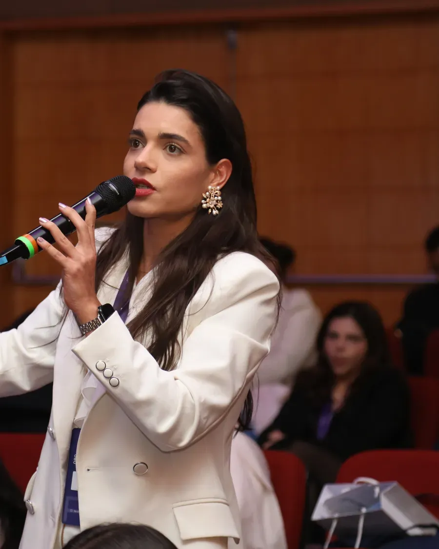 Médica de pé fazendo uma pergunta ao microfone durante um encontro da R+