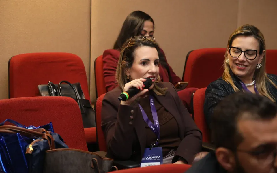 Médica fazendo uma pergunta ao microfone durante um encontro do R+