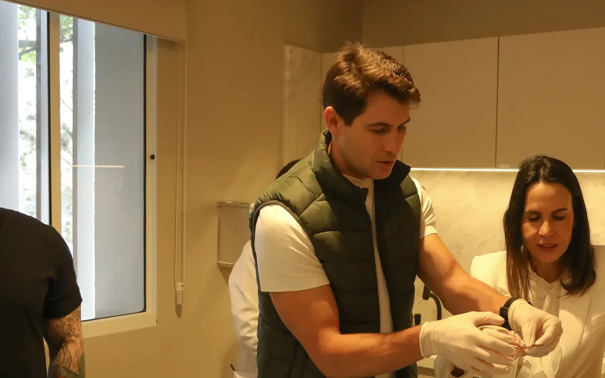 Mentor de luvas orientando uma aluna na preparação do material, num curso prático