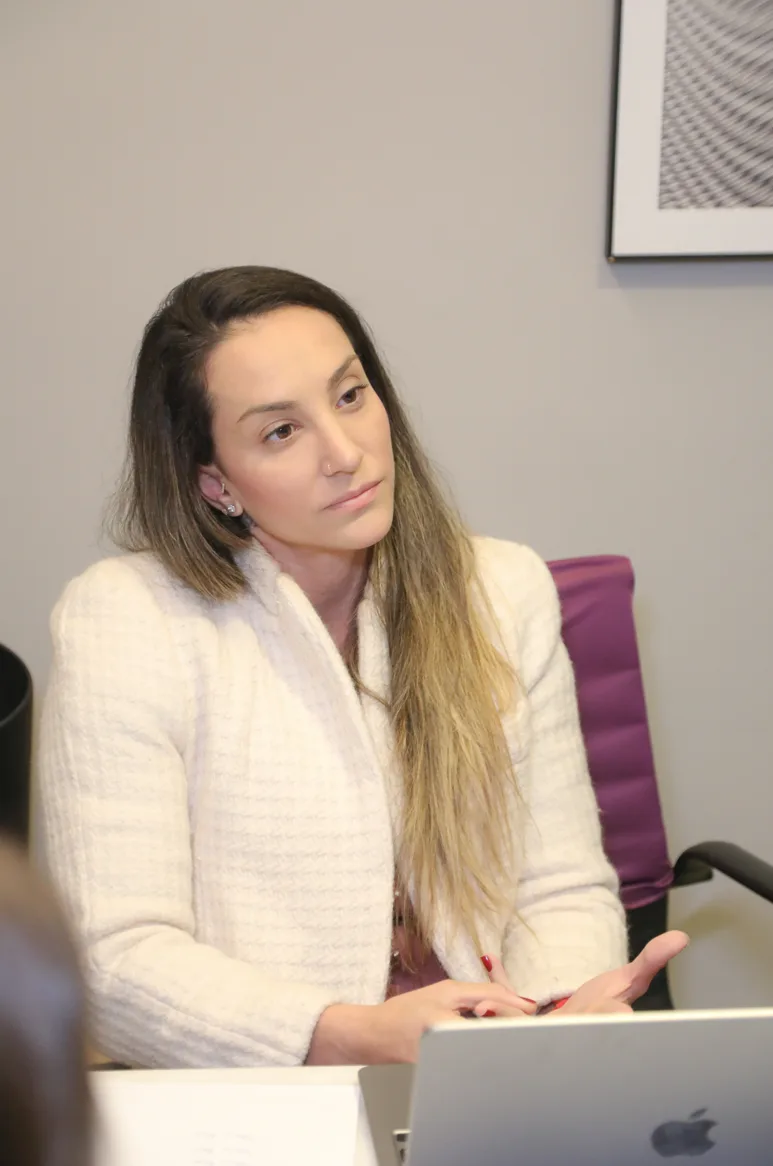 Mentora sentada ao notebook num consultório, falando com quem acompanha